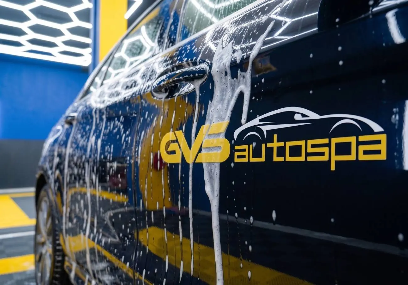 A black car covered in foam, GVS autospa decal on the door