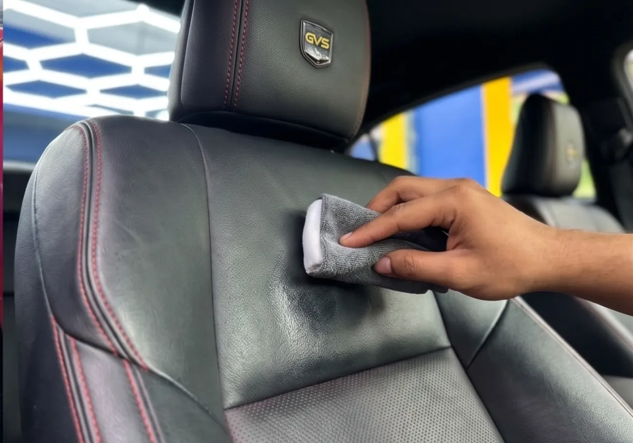 Wiping down a leather seat during interior detailing